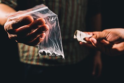 Photo of hands holding a baggie of pills and cash