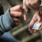A drug deal with one person holding cash, and the other holding drugs.