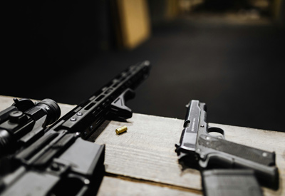 Weapons laying on a table with empty bullet casings around the guns.